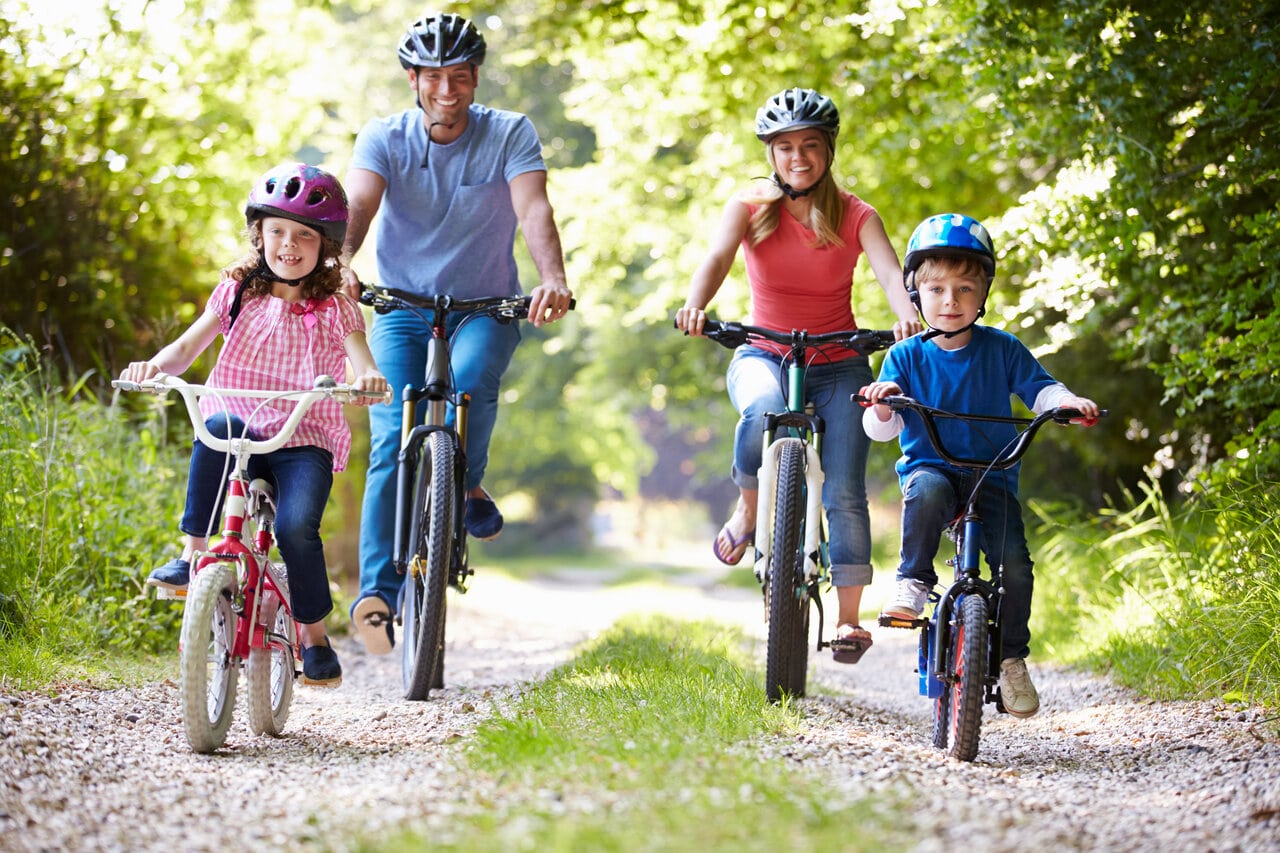 Family of four riding bikes on forest trail